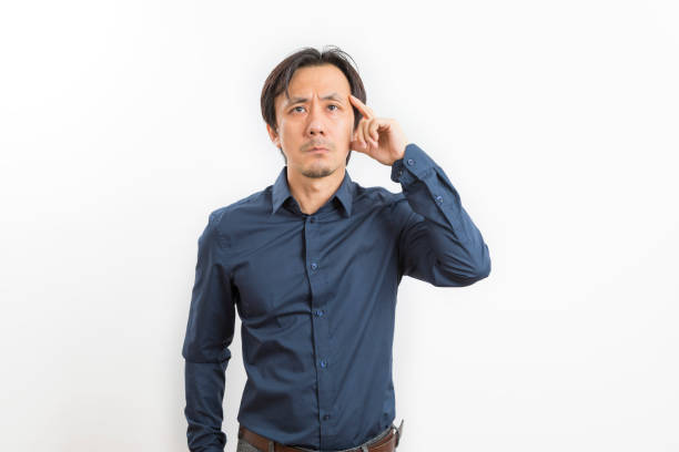Middle-age Asian man in black shirt thinking, on isolated white background.