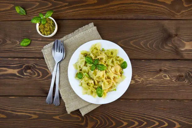 Farfalle pasta with pesto sauce on a wooden background Top view, copy space.