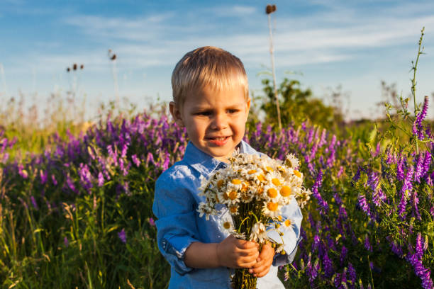 istock Cute Boy Holding Bouquet While Standing On Field 1317257221