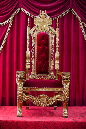 Red royal chair on a background of red curtains. Place for the king. Throne