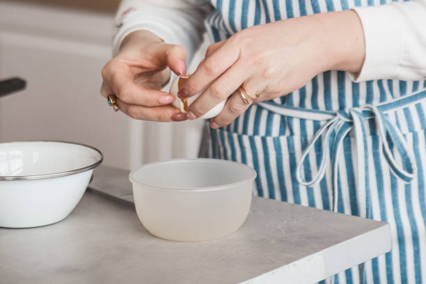 istock Girl in a blue apron breaks an egg, prepares dessert or scrambled eggs 1317258910
