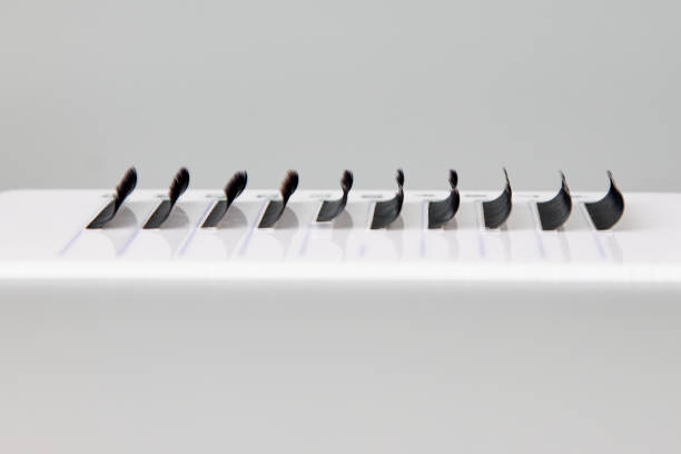 A tablet with false eyelashes on a gray background. A tablet with false eyelashes on a gray background. Cosmetic accessories for eyelash extensions clump eyelashes stock pictures, royalty-free photos & images
