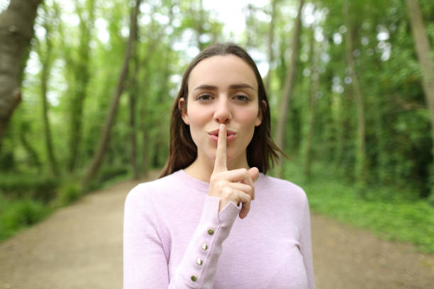Beautiful woman asking for silence in a forest