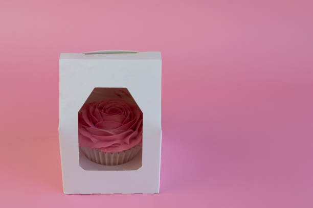 istock horizontal image with a delicious rose cupcake in a gift box on a pink background. 1317262858