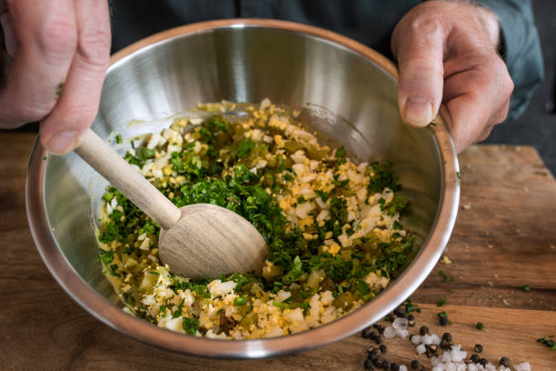 Preparing a gribiche sauce Preparing a gribiche sauce for green asparagus. Hands stir fresh ingredients in a bowl for a tasty side dish. Gastronomy and lifestyle background. Close up. tarragon horizontal color image photography stock pictures, royalty-free photos & images