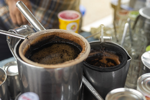 Close-up, black coffee water bags in a vintage stainless steel pot set up for brewing, sold in a cart, which is common in rural Thailand