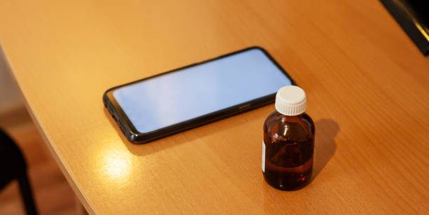インターネット経由で携帯電話で液体医療薬を注文するという概念。背景に白い画面を持つスマートフォン - digital tablet document technology nobody ストックフォトと画像