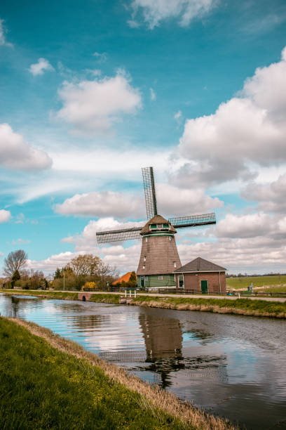 lone windmill near river in the netherlands - zaanse schans bridge house water imagens e fotografias de stock