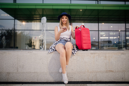 Woman tourist waiting on the street, texting on the phone,  summer fashion style