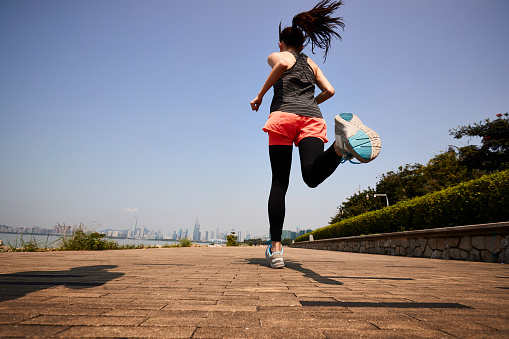 young asian adult woman running jogging outdoors, rear and low angle view