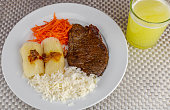 Brazilian food dish with steak and rice and carrots and cassava with an eye. Executive lunch