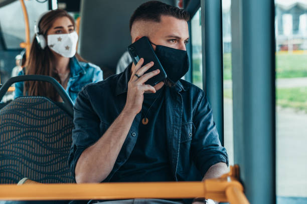 istock Man wearing face protective mask and using a smartphone in the bus 1317275132