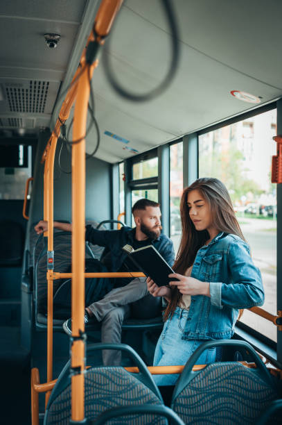 femme affichant un livre tout en restant dans le bus en mouvement - bus inside of people train photos et images de collection
