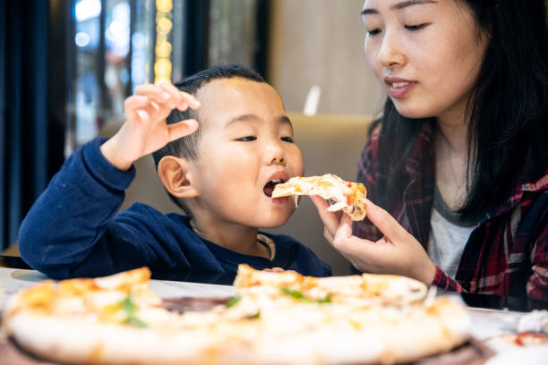 istock Mother feeding her son eating pizza 1317275874