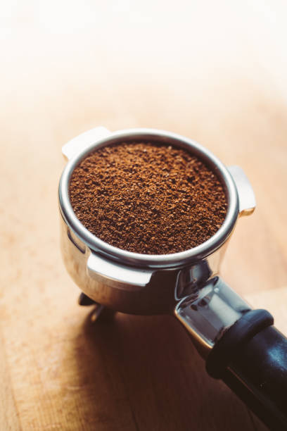 Portafilter with grounded coffee and coffee beans close-up