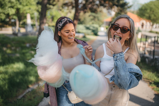 Happy women eating pink cotton candy