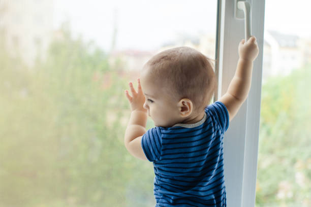 istock Rear View Of Boy Standing By Window 1317277521