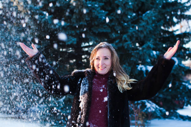 istock Smiling Woman Throwing Snow Outdoors During Winter 1317278585