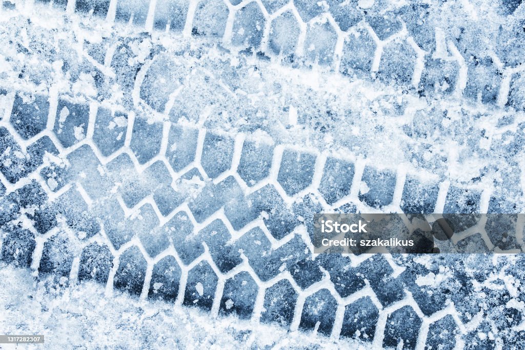 Snow tyre mark. Asphalt covered in snow. Dangerous road conditions. Car imprint on frozen ground. Tire trail on ice. City streets covered in snow during heavy snow fall. Slippery road background. Snow Stock Photo