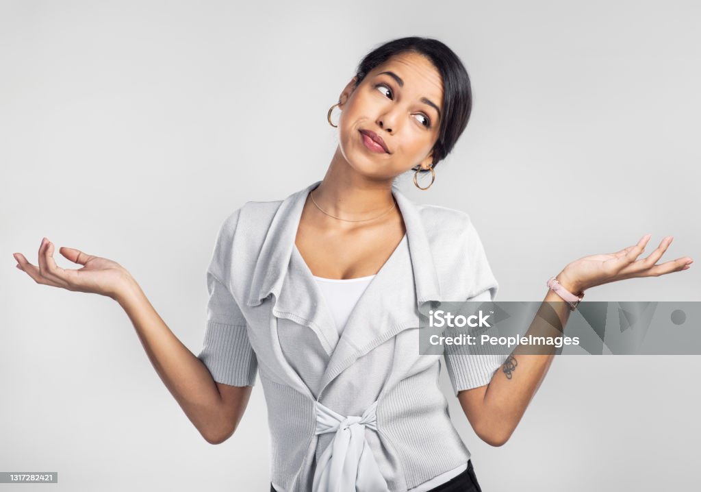 Studio shot of a young businesswoman shrugging her shoulders against a grey background If you missed it, maybe it wasn’t for you Shrugging Stock Photo