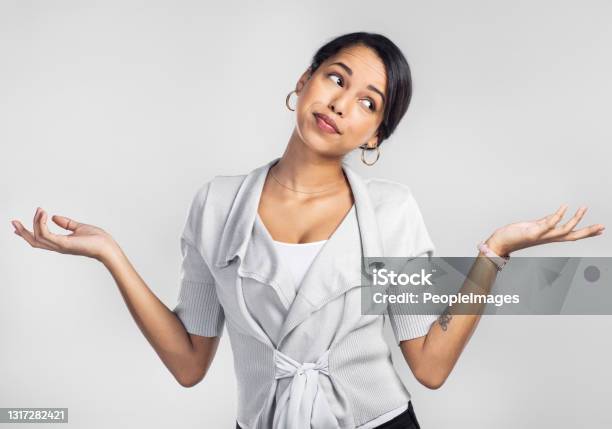 Studio Shot Of A Young Businesswoman Shrugging Her Shoulders Against A Grey Background Stock Photo - Download Image Now