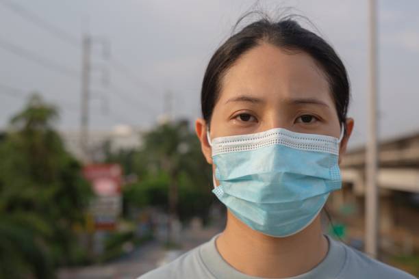 istock A woman wearing a surgical mask is standing on a flyover. 1317282509
