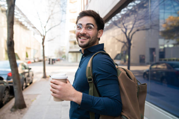 Young man holding a cup of coffee while walking outdoors.