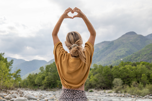 Young woman loving nature, she makes heart with hands