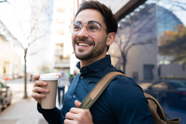 istock Young man holding a cup of coffee while walking outdoors. 1317283892