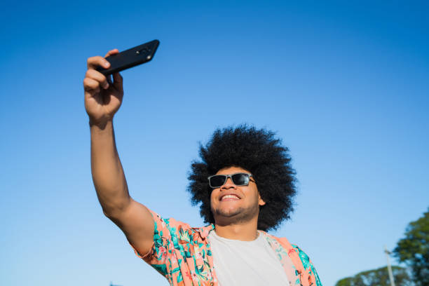 istock Latin man taking a selfie with phone outdoors. 1317284032