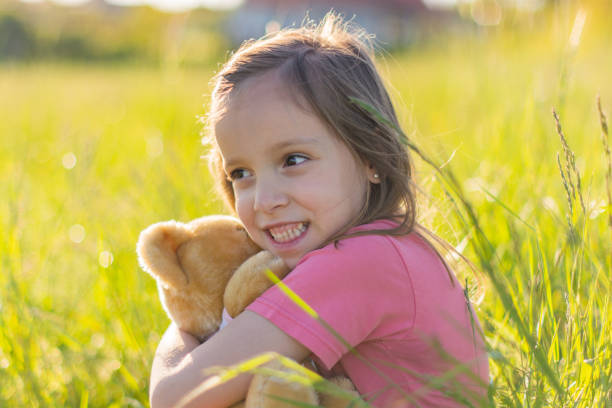 Cute little girl embracing her teddy bear outdoors