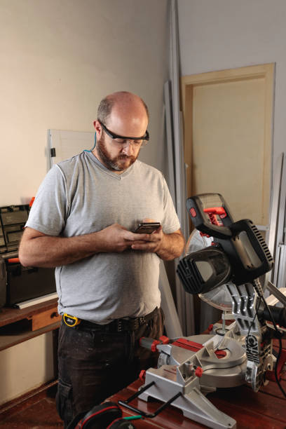 istock Worker in carpentry workshop sending a message by smart phone 1317288710