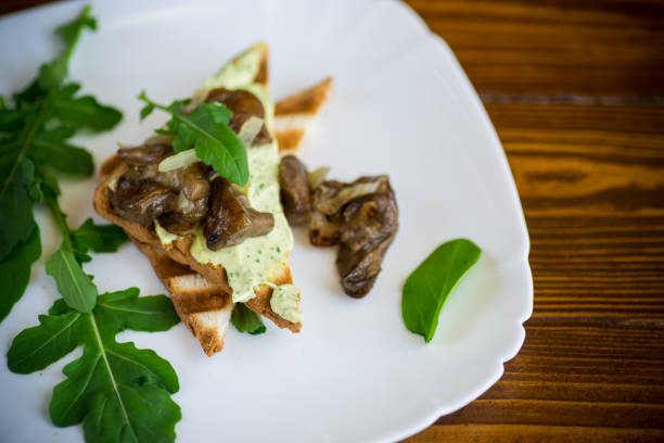 fried toast with cheese spread, arugula and fried mushrooms in a plate