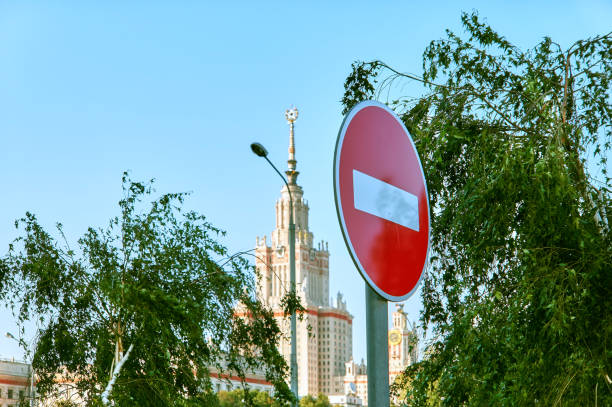 segnale di stop rosso sullo sfondo del cielo blu e silhouette della famosa università di mosca in primavera - università di mosca foto e immagini stock