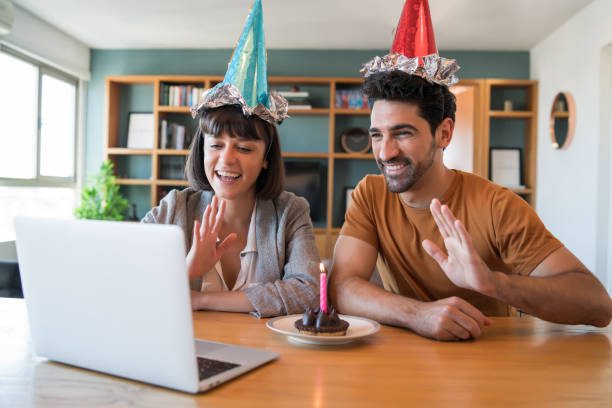 Couple celebrating birthday on a video call at home. Portrait of a couple celebrating birthday on a video call with a laptop from home. Couple celebrating birthday online in quarantine time. New normal lifestyle concept. virtual birthday celebration stock pictures, royalty-free photos & images