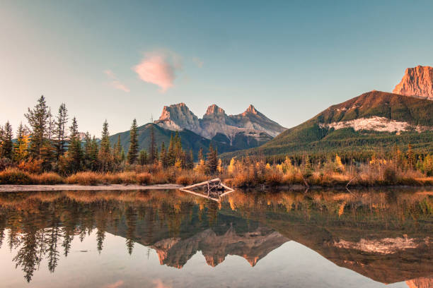 バンフ国立公園のカンモアで朝、ボウ川に反射する岩の山の3人の姉妹の山 - dawn mountain range mountain canadian rockies ストックフォトと画像