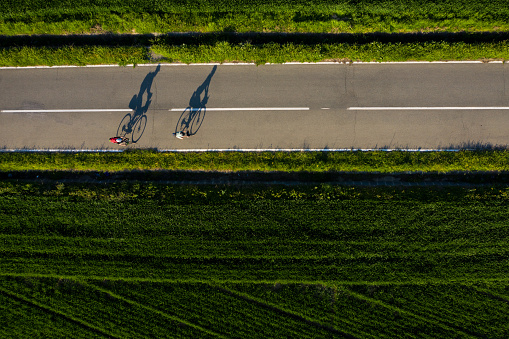 Drone shot of two cyclist and their shadows projecting on the road at sunset