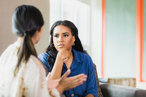 During a counseling session, the  unrecognizable mid adult female patient gestures while speaking.  The mid adult female therapist listens attentively.