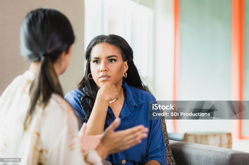 Unrecognizable female patient gestures as female therapist listens attentively During a counseling session, the  unrecognizable mid adult female patient gestures while speaking.  The mid adult female therapist listens attentively. Listening Stock Photo
