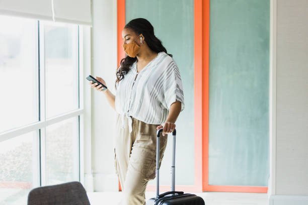istock Woman casually stands with hand on suitcase to text message 1317309320
