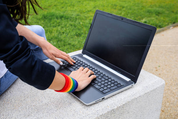 Close-up of woman hands with laptop and LGBT bracelet in modern park . LGBTQIA culture. Close-up of woman hands with laptop and LGBT bracelet in modern park . LGBTQIA culture. bracelet photos stock pictures, royalty-free photos & images