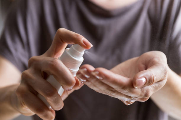 Close up view of woman person using small portable antibacterial hand sanitizer on hands. Coronavirus epidemic prevention concept. Woman applying spray disinfection alcohol product on hand. Disinfecting hands against virus bacteria, health prevention in day at home or work. antiseptic stock pictures, royalty-free photos & images