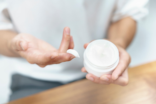 Man picking up white cream for beauty care
