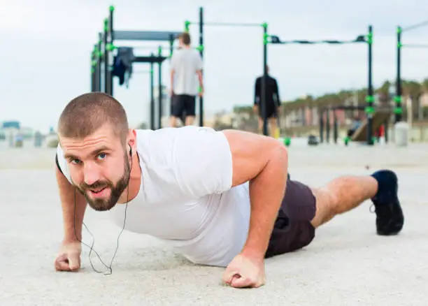 Strong man performs push-ups on an outdoor sports field