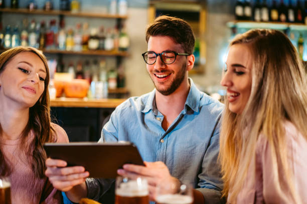 istock Two young women and man using tablet 1317312260