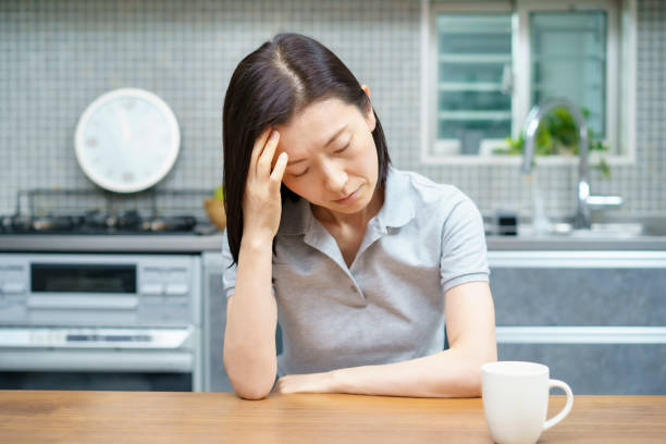 Middle-aged woman suffering from headache Asian middle-aged woman suffering from headache in the room asian woman around 50s menopause stock pictures, royalty-free photos & images