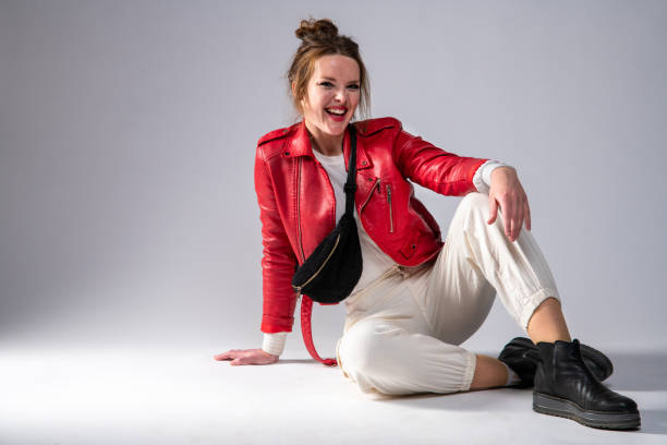 Cute woman in red leather jacket on gray background.