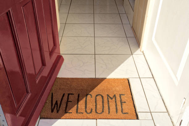 Open front door of house with Welcome door mat entering in the Hallway of a modern new home Open front door of house with Welcome door mat entering in the Hallway of a modern new home sunlight key doormat stock pictures, royalty-free photos & images