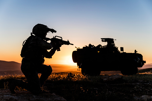 Battlefield with a soldier and armored vehicle at sunset