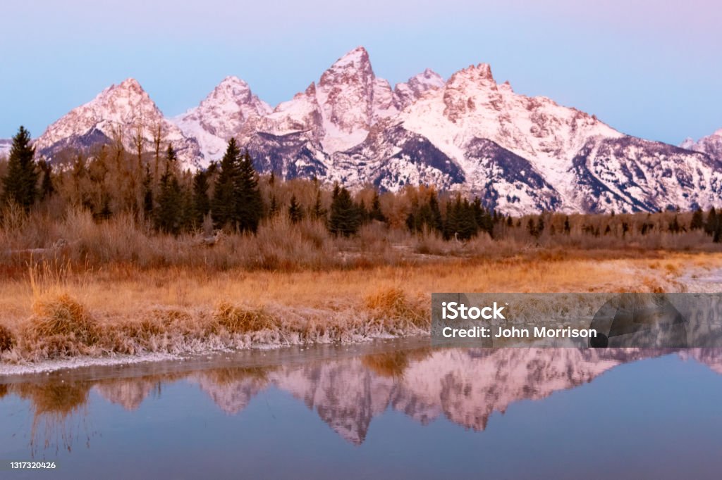 Early morning Tetons mountains with reflection Reflection on the Snake river of the Teton peaks of Grand Teton National Park in Wyoming, western USA. Nearest town is Jackson, Wyoming. Teton Range Stock Photo